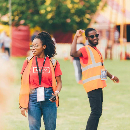 2 people wearing orange hi-vis vests working at a festival